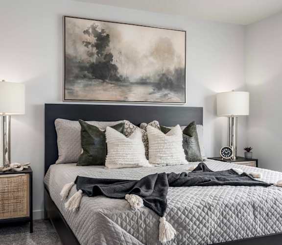 A bedroom with a large bed and a painting above it.
