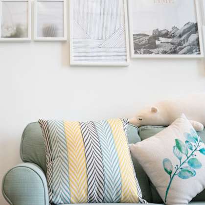 a living room with a couch and a plant and pictures on the wall