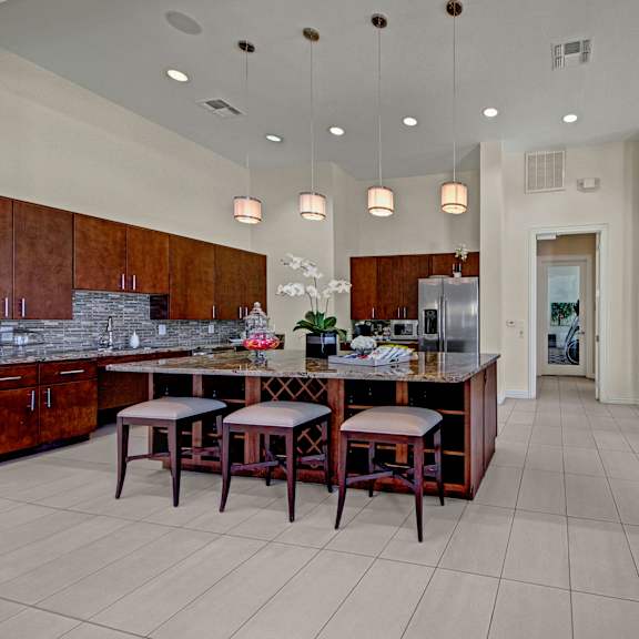 The community kitchen, complete with a sink, a fridge, counters, and barstools at Le Mirage Apartments. 