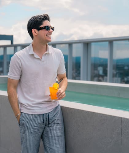 a man standing on a roof holding an orange juice