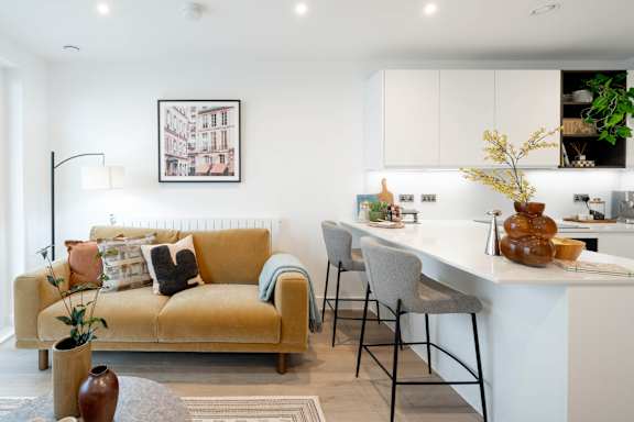 A living room with a yellow couch and a white kitchen in the background.