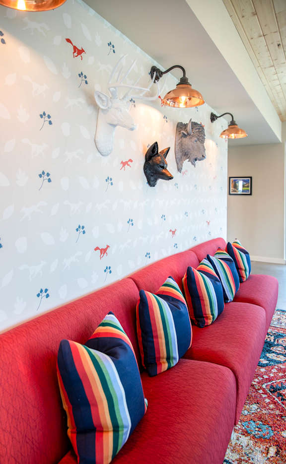 a long red couch with pillows in front of a white wall