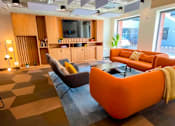 Thumbnail 9 of 16 - a large living room with orange couches and a television