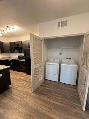 an open door leading to a laundry room with two washers and a dryer
