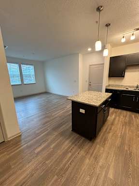 an empty kitchen and living room with a granite counter top