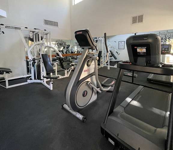 A gym with a treadmill, elliptical trainer and other exercise equipment.