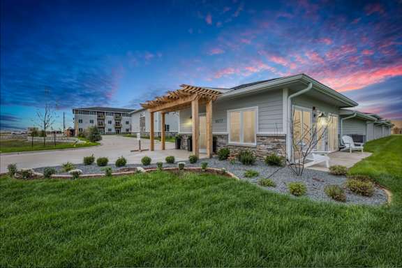 A modern house with a wooden pergola and a well-maintained lawn.
