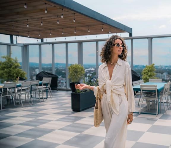 a woman in a white dress standing on a roof top restaurant