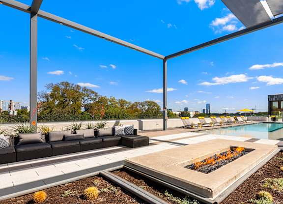 A modern outdoor seating area with a pool and a view of the city.