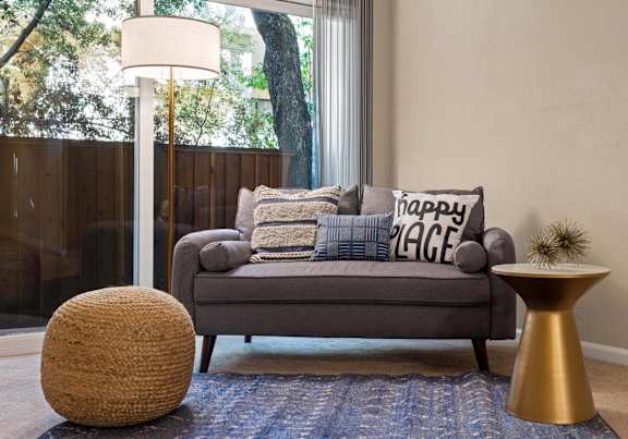 A grey couch with a pillow that says "Happy Valley" is in front of a window.