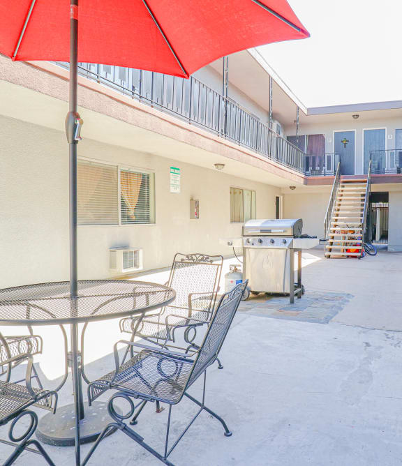 a patio with a table and chairs and a red umbrella