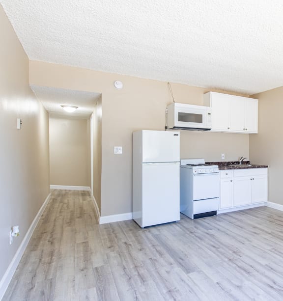 an empty kitchen with white appliances and a microwave and refrigerator