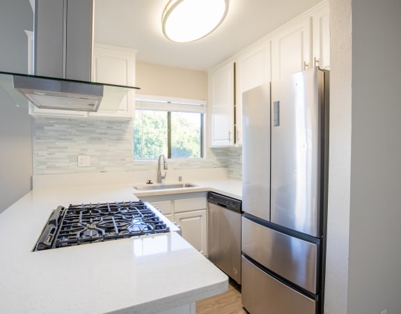 an updated kitchen with stainless steel appliances and white countertops