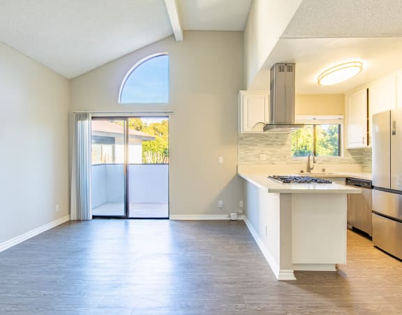 an empty kitchen with a stainless steel refrigerator and a sink