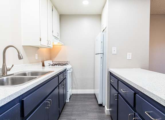 an empty kitchen with blue cabinets and a sink and a refrigerator