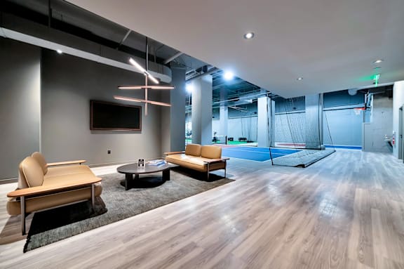 A modern living room with a wooden floor and a television on the wall.