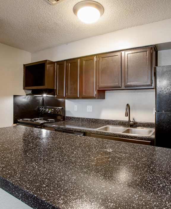 A kitchen with black appliances and brown cabinets.