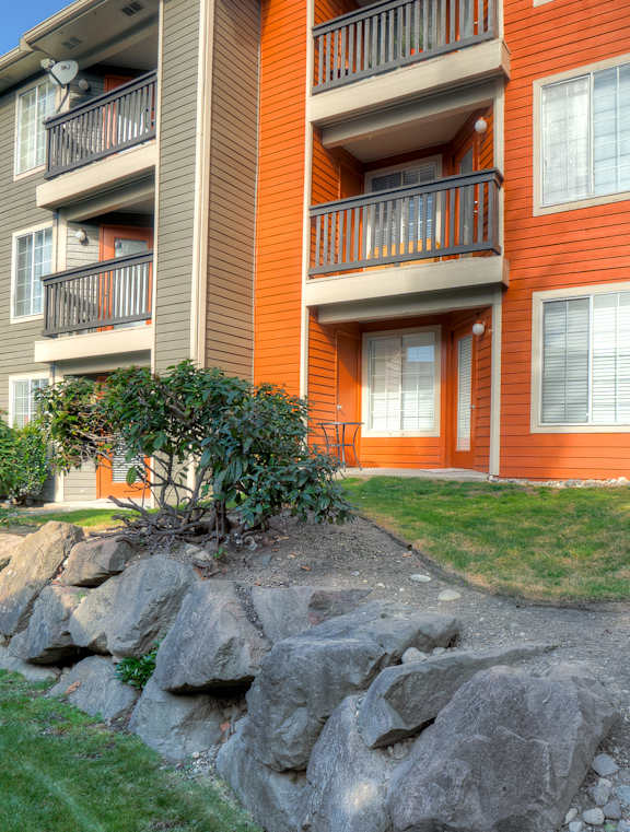 A red and beige apartment building with a stone wall in front.