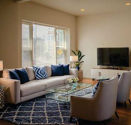 A living room with a couch, chairs, and a television.
