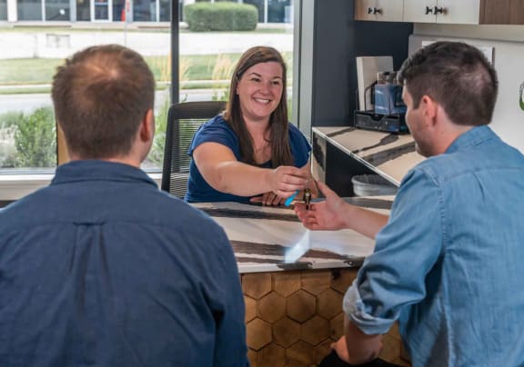 a two men at a leasing desk talking to a leasing agent holding keys