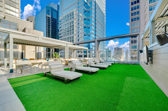 A rooftop patio with white lounge chairs and a green carpet. at 17 Market West, Philadelphia, PA 19103