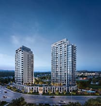 Two tall buildings are surrounded by trees and a parking lot.