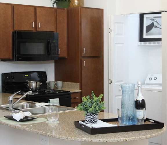A kitchen with brown cabinets and a black microwave.
