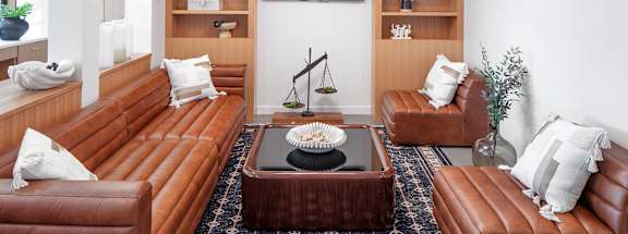A living room with brown leather furniture and a rug.