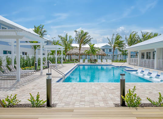 a swimming pool in front of a resort with white buildings