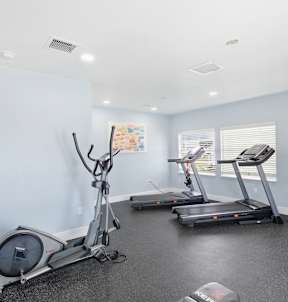 A room with a treadmill, elliptical trainer and a stationary bike.