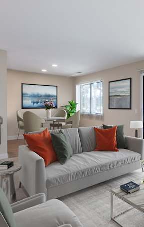 A living room with a grey couch, a glass coffee table, and a painting on the wall.