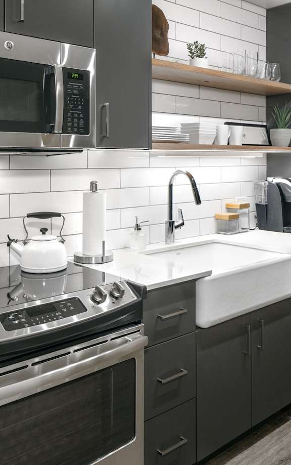 Luxury 2 BR Apartments in Portland OR - Couch9 Apartments - Modern Kitchen with Stainless Steel Appliances, Quartz Countertops, Tile Backsplash, Grey Cabinetry, and Hardwood Flooring