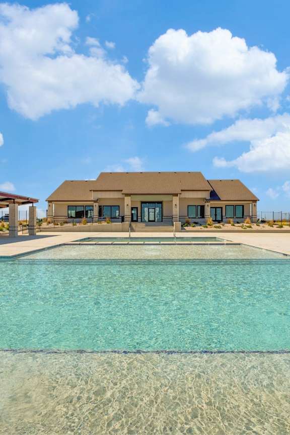 A large swimming pool in front of a house.