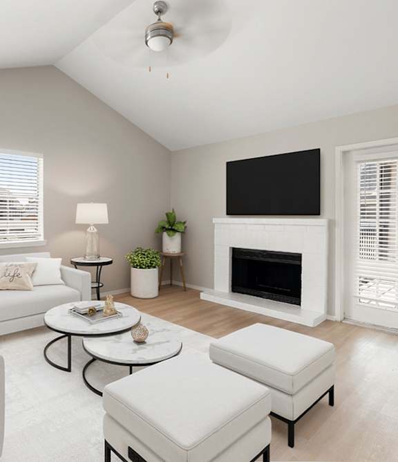A living room with a white couch, a coffee table, and a fireplace.