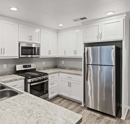 A kitchen with white cabinets and a stainless steel refrigerator.