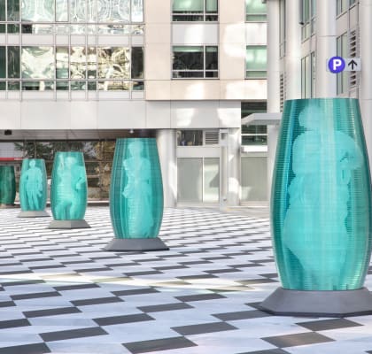 a row of turquoise coloured sculptures in front of a building