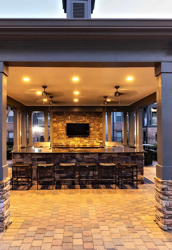 A stone and tile patio with a fireplace and seating area.