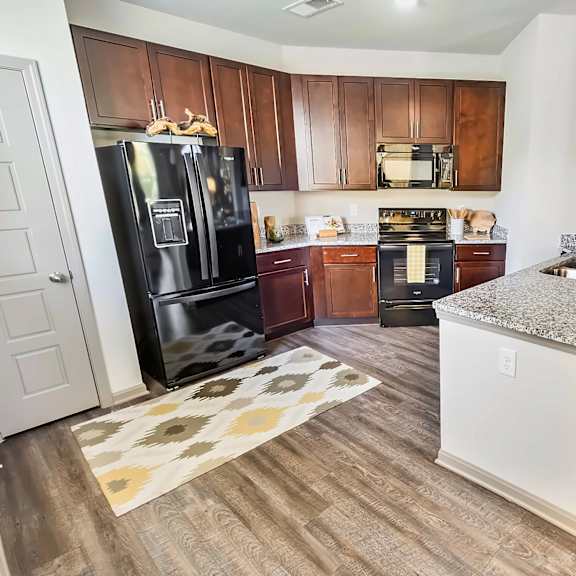 A kitchen with a black fridge and wooden cabinets.
