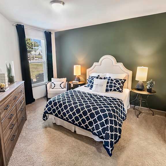A bedroom with a bed, nightstand, and a mirror on the wall.