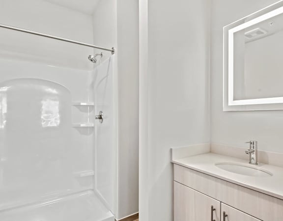 a bathroom with a shower and a sink and a mirror at Metropolis Apartments in Glen Allen, VA