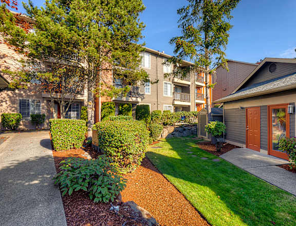 A sunny day at a residential area with apartment buildings and well-maintained lawns.