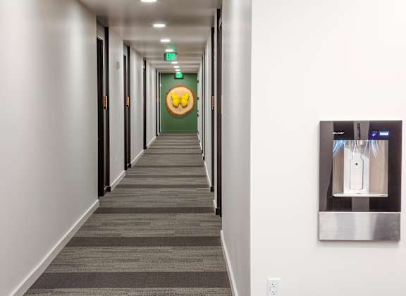 a long hallway with white walls and gray carpet and a yellow smiley face door at The Weidler in Portland, OR 97209