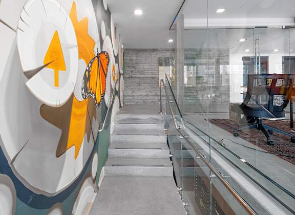 a lobby with a staircase and a large mural on the side of a glass wall at The Weidler in Portland, OR 97209