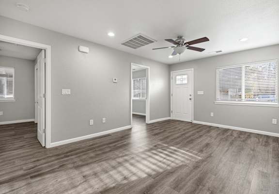 A room with a ceiling fan and hardwood floors.