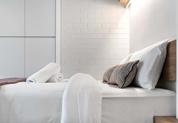 a white bed with pillows and blankets in a small room