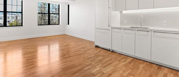 A room with white cabinets and wooden flooring.