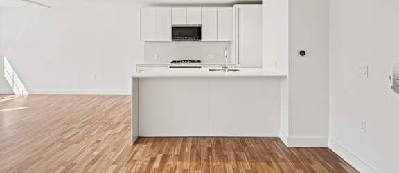 an empty living room and kitchen with white walls and wood floors