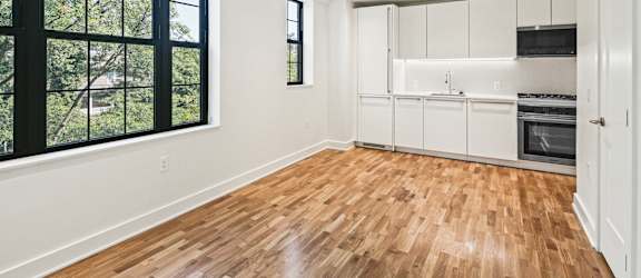 an empty living room with a kitchen and a large window