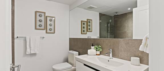 A white bathroom with a toilet, sink, and mirror.