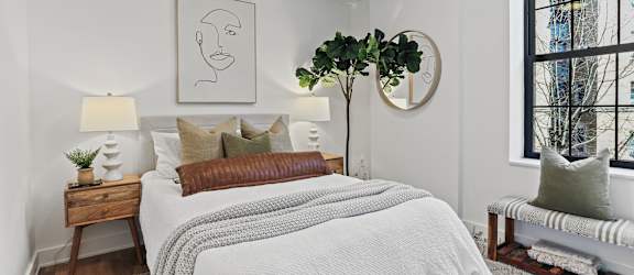 A bedroom with a large bed and a window overlooking a city.